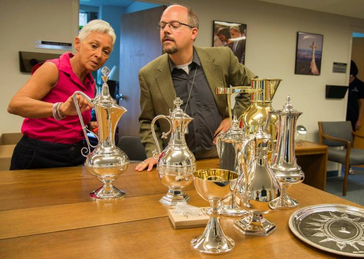 Officials of Washington National Cathedral inspecting several antique liturgical vessels, returned to the cathedral this week after being restored. The biggest one is a brass baptismal ewer; all will be returned to use in worship. (cathedral photo)